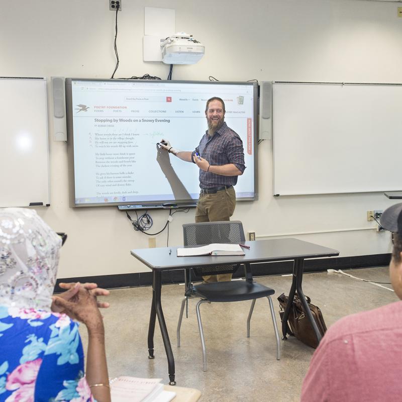 English teacher writing on the board and smiling at the class 