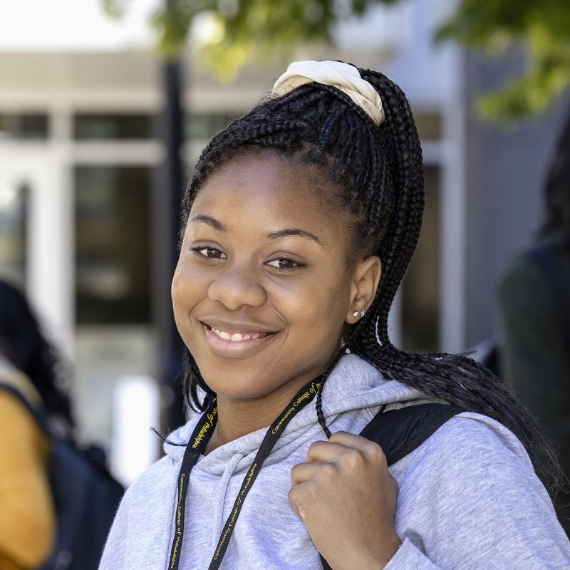 A student standing outside looks confidently at the viewer.