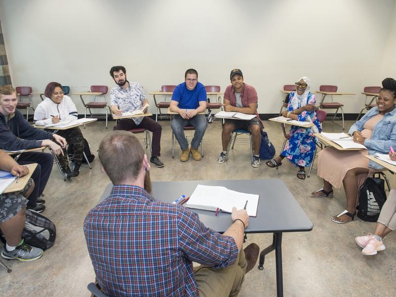 Circle of students at desks writing together during class