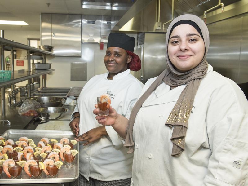 Two culinary arts students smiling with their shrimp cocktail dishes