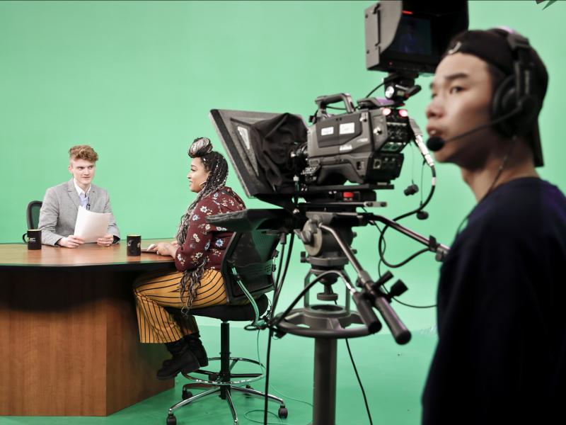 Students behind the scene on a green screen set 