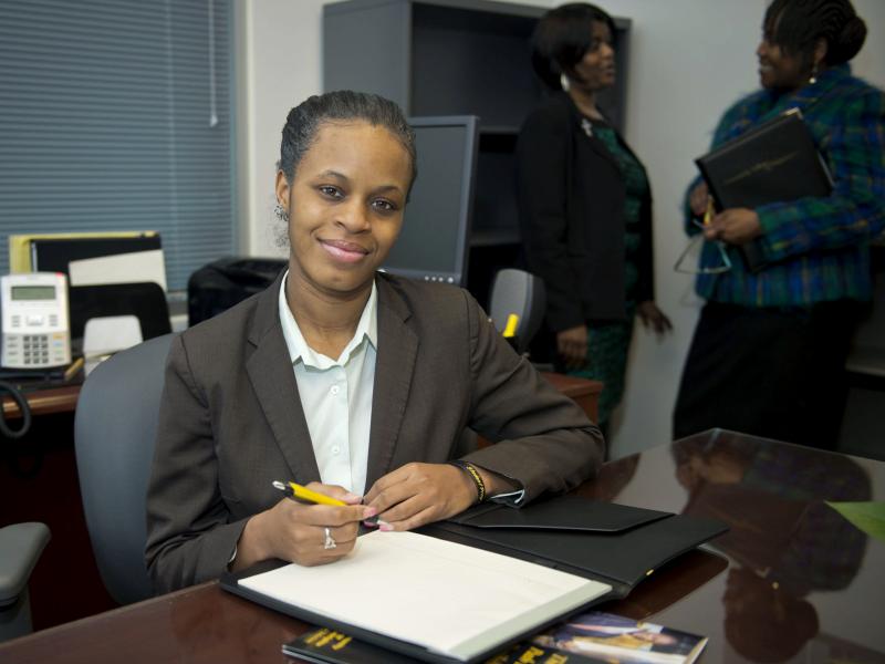 A student smiles at the camera with an open notebook.