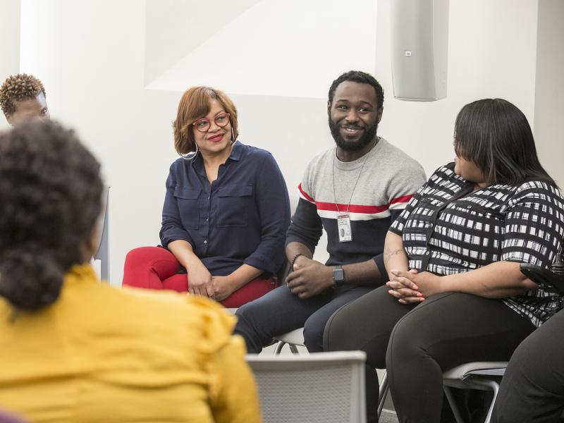 Group sitting in a circle react with smiles to person speaking.