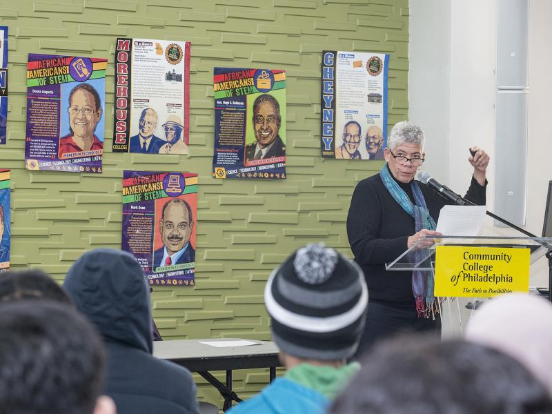 Instructor speaks to students with posters of prominent Black leaders on the wall.