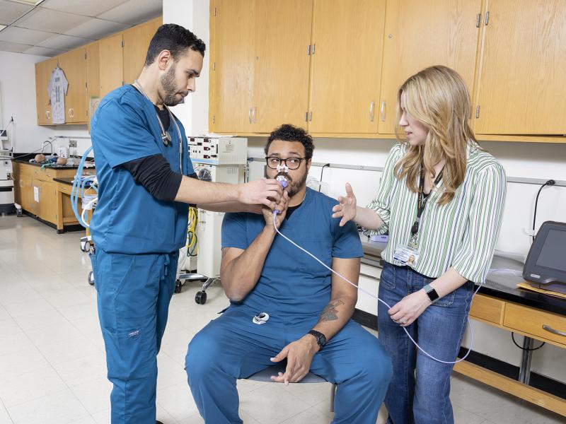 Instructor explains equipment as one student plays patient and one student plays therapist.