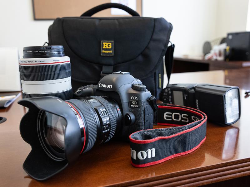 Image of camera, lens, flash and camera bag on a table.
