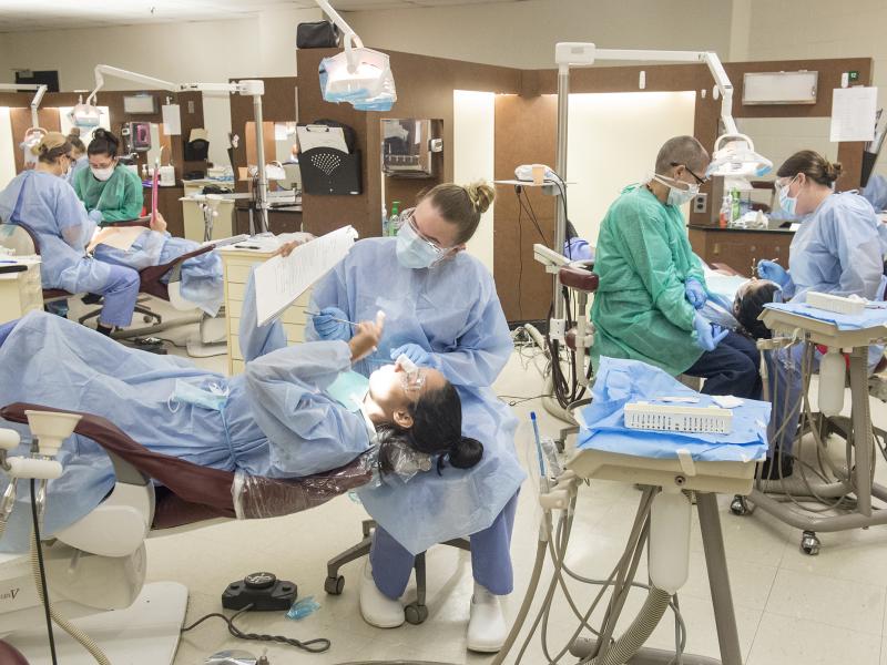 Dental hygiene students working on one another in a dental clinic.