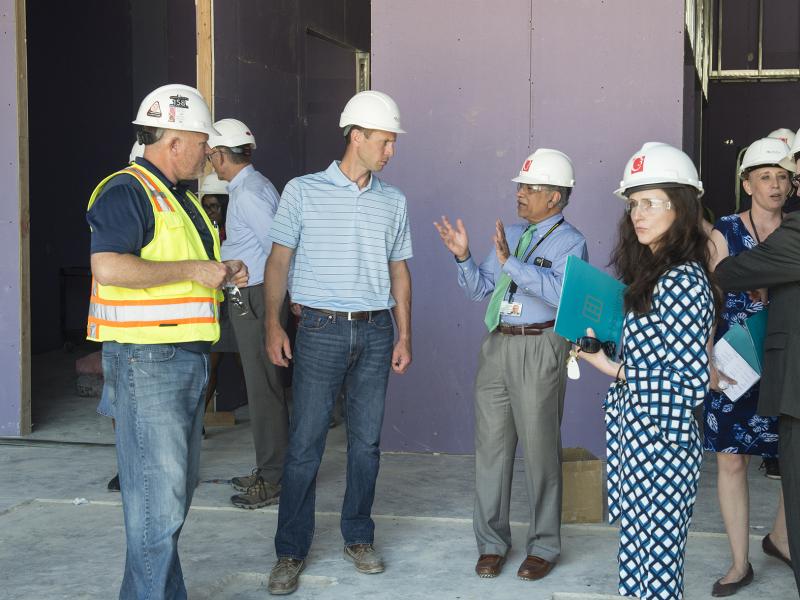 A group of inspectors in construction helmets tour a building under construction.