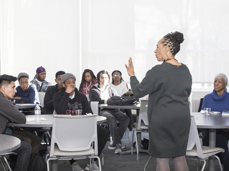 Speaking talks to students who are listening intently.