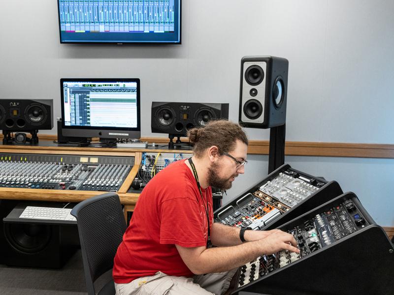 Student Works at sounding board surrounded by recording equipment.