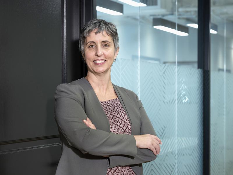 Woman in business attire stands confidently in an office hallway.