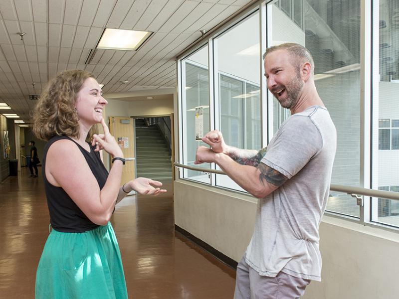 Smiling students communicating via American Sign Language at the College