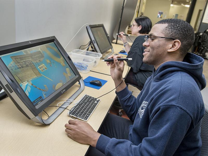 A student sits working on an architectural virtual reality interface in the design lab