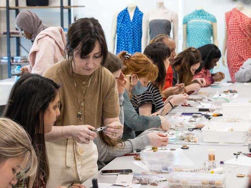 Students making jewelry in a classroom.