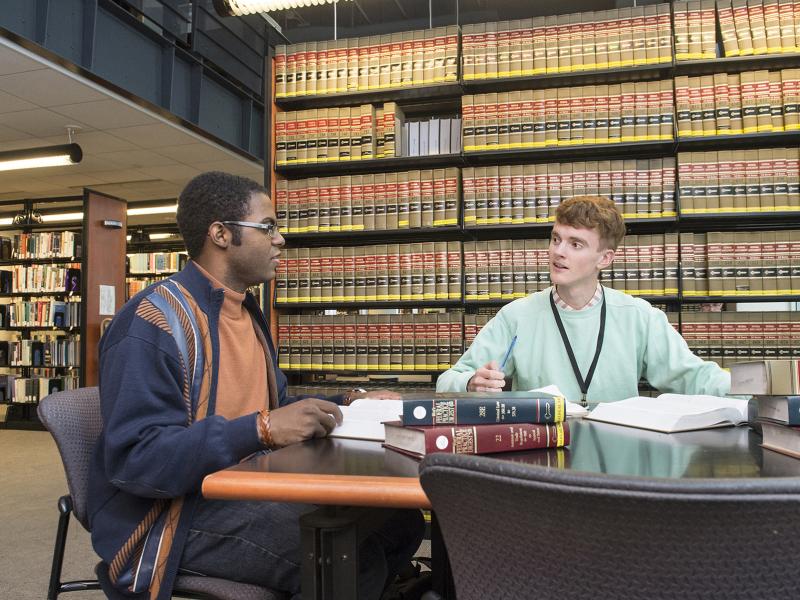 Two students student in a library of legal books.