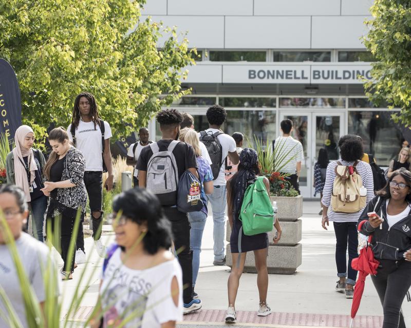 a flurry of students walking in front of the Bonnell Building on a nice day.