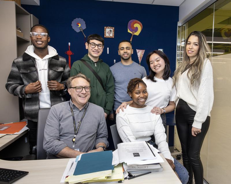 International students sitting with teacher in an office. 
