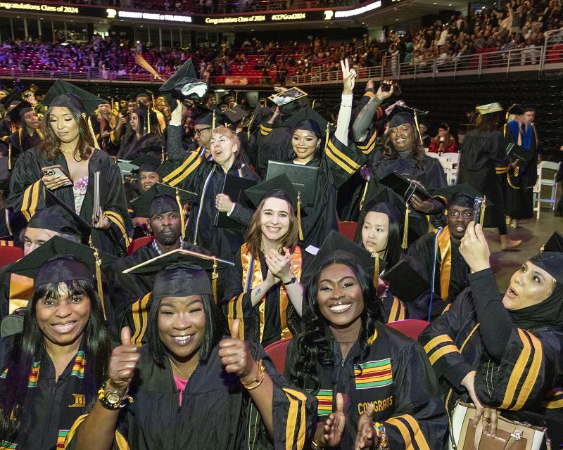 Students smiling at the camera at graduation