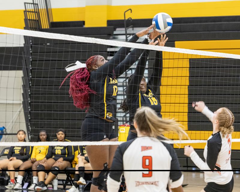 Volley ball player blocking the other teams attempt to score in a match 