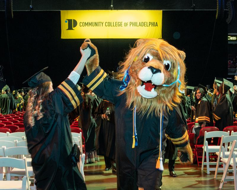 Roary high-fiving a student at graduation