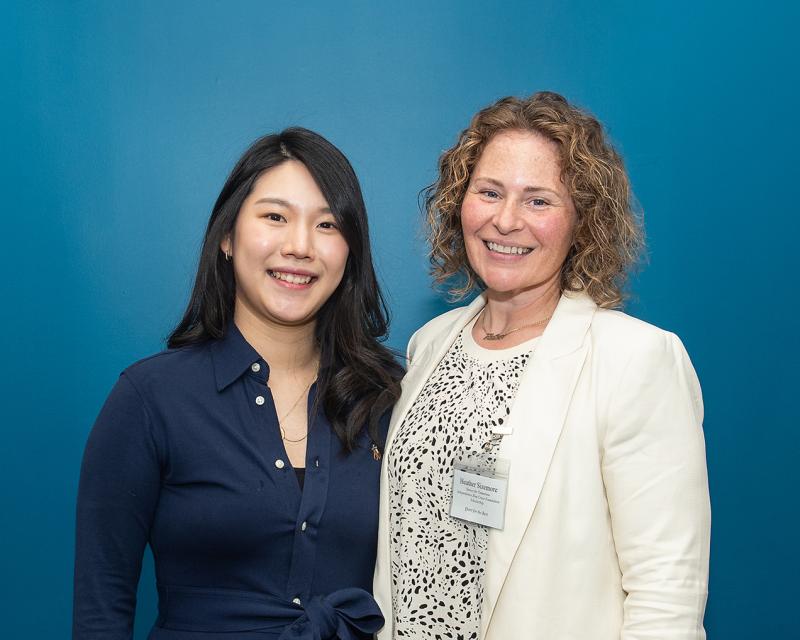 Two alumni smile at the camera.